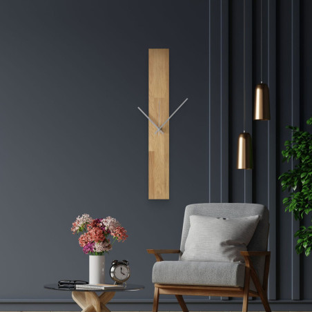 Moderní nástěnné hodiny, nalepené na bílé stěně, s jednoduchými černými ručičkami.