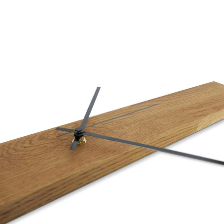 Minimalistické hodiny ze dřeva ve tvaru úzkého panelu se stříbrnými a černými ručičkami.