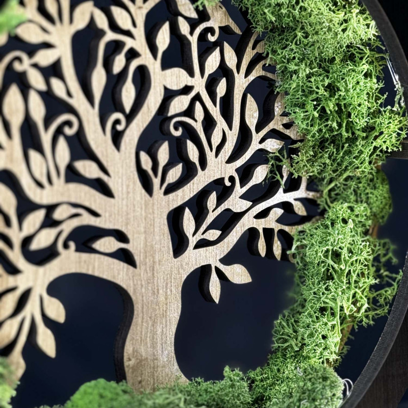 Detailní pohled na podsvícený dřevěný Strom života obklopený mechem.