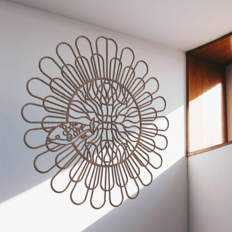 Černá dřevěná mandala s rybou na bílé stěně v moderním bytě