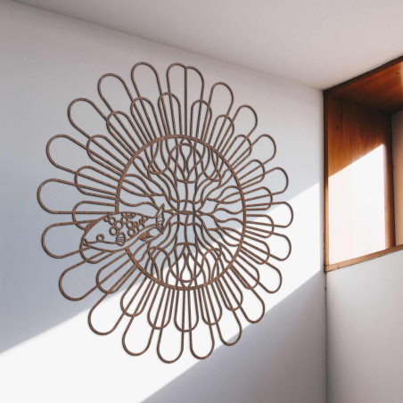 Černá dřevěná mandala s rybou na bílé stěně v moderním bytě